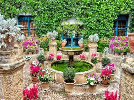 Cortile fiorito con fontana, ideale dove andare in primavera per ammirare la bellezza della natura.