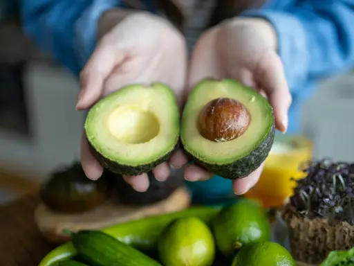Hände halten eine aufgeschnittene Avocado. Tipps für avocado haltbar machen.