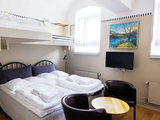 Ett mysigt rum på Langholmen Hotel med våningssängar, dubbelsäng, konst och TV.