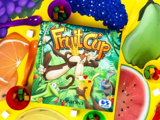 Gra Fruit Cup z owocami i kostkami. Małpa w koronie miesza owocowy deser.