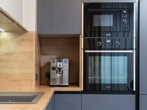 Eleganckie, nowoczesne **miejsce na ekspres do kawy w kuchni**, obok wbudowanego piekarnika i mikrofalówki.