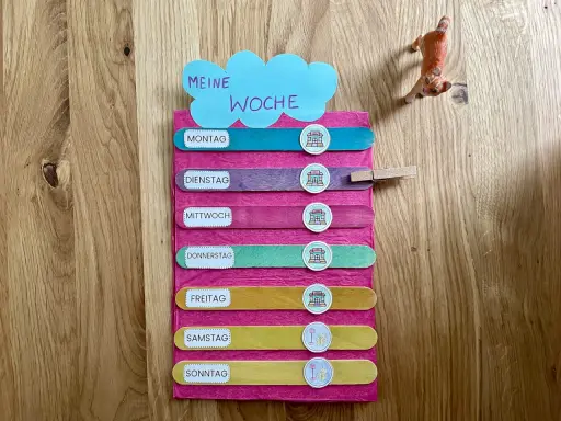 Montessori-Tafel zum Wochentage lernen. Bunte Holzstäbchen mit den Tagen der Woche und Symbolen.