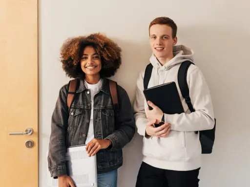 Dwóch studentów, dziewczyna z kręconymi włosami i chłopak, przygotowuje się do nauki. Może właśnie szukają informacji, jak napisać artykuł po angielsku.