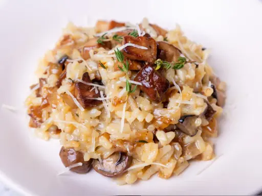 Aksamitne risotto z grzybami, posypane parmezanem i gałązkami tymianku, kusi apetycznym wyglądem.