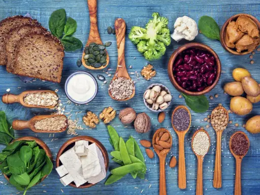 Różnorodne produkty bogate w białko dla wegetarian: tofu, soczewica, fasola, orzechy, nasiona, płatki owsiane, ryż, chleb pełnoziarnisty, jogurt, szpinak, brokuły, kalafior.