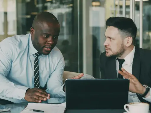 Deux hommes d'affaires discutent d'une nouvelle démarche, synonyme de succès. Ils sont concentrés sur une tablette.