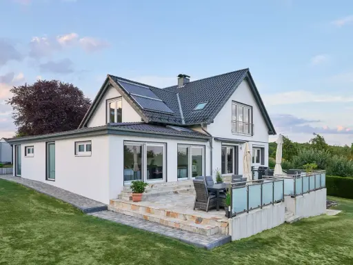 Modernes Haus mit Anbau und Terrasse. Die Solaranlage auf dem Dach deutet auf niedrige Energiekosten hin.