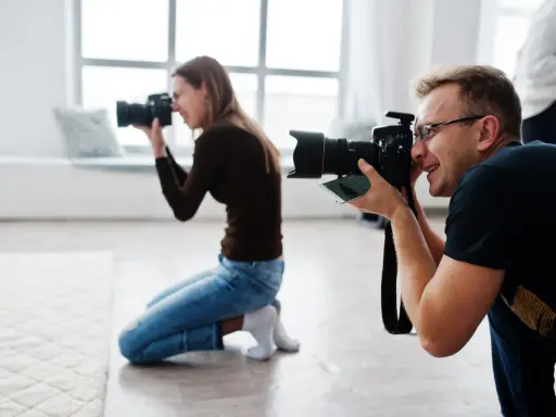 Mężczyzna i kobieta uczą się, jak zostać fotografem, ćwicząc z aparatami w studiu.