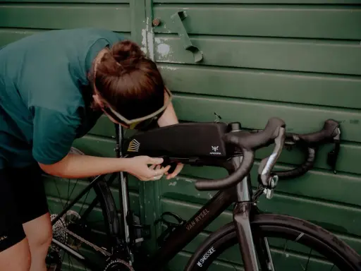 Osoba montuje torbę podsiodłową do roweru. Przygotowania do składania roweru przed wyprawą.