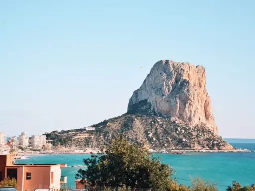 Widok na majestatyczną skałę Peñón de Ifach, symbol Costa Blanca atrakcje. Turkusowe morze i zabudowania miasta tworzą malowniczy krajobraz.