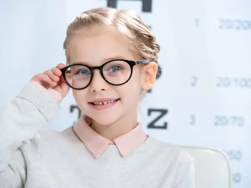 Uśmiechnięta dziewczynka z okularami, u której wykryto bardzo dużą wadę wzroku u dziecka.
