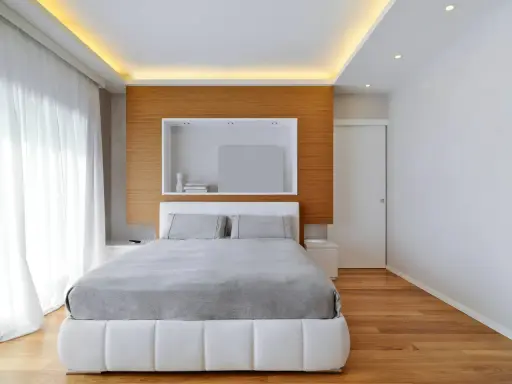 Illuminazione a scomparsa nel controsoffitto, un'idea moderna per un soffitto elegante. Camera da letto minimalista con letto bianco e testiera in legno.