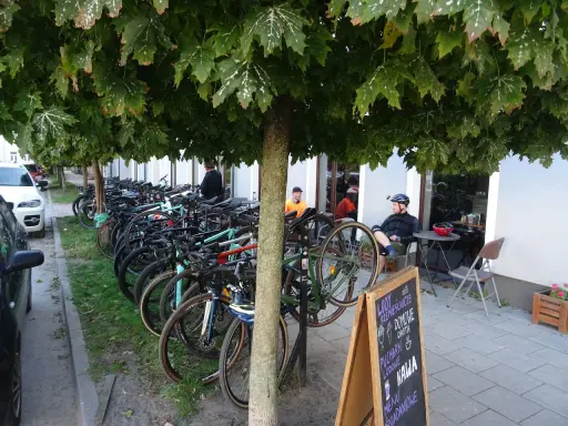 Rowerzyści odpoczywają pod drzewami w Górze Kalwarii. Rzędy rowerów czekają na dalszą trasę.