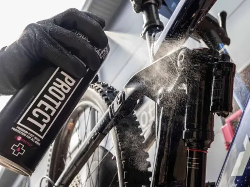 Rękawica z puszką "PROTECT" rozpyla środek na ramę roweru elektrycznego, pokazując, jak myć rower elektryczny.
