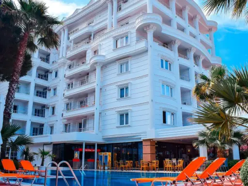 Biały hotel z balkonami i basenem, otoczony palmami. Idealne miejsce na fafa mel holiday.