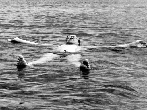 Tage Erlander, statsminister, flyter avslappnat på rygg i vattnet, med armarna utsträckta.