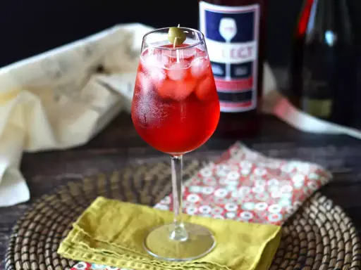 Un verre de spritz vénitien, rafraîchissant et pétillant, garni d'une olive. Parfait pour un apéritif ensoleillé.