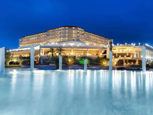 Elegancki Starlight Resort Hotel nocą, z oświetlonym basenem i palmami.