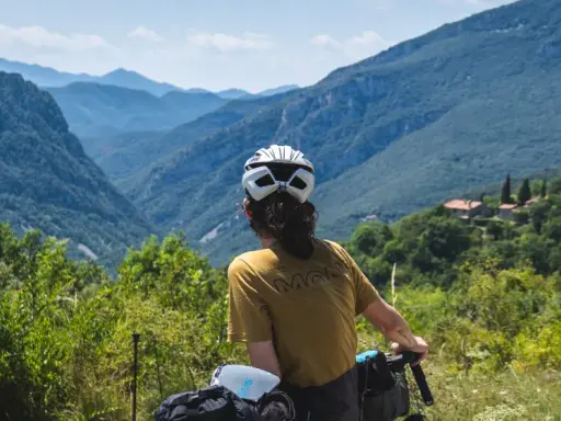 Rowerzysta podziwia malownicze góry między Francją a Hiszpanią. W oddali widać domy na zboczu.