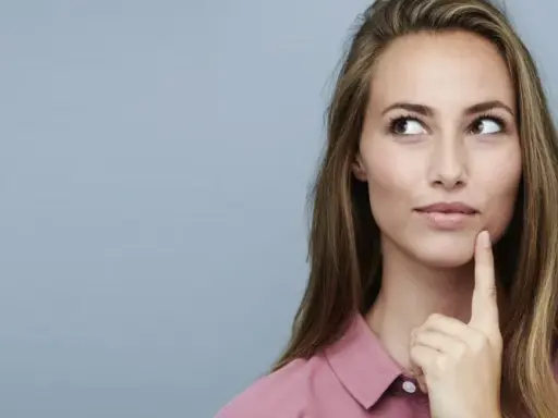 Nachdenkliche Frau mit langen Haaren, die über die Vorteile von Keratin und Kreatin für die Haargesundheit sinniert.