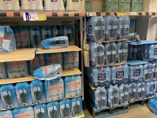 Scaffali pieni di bottiglie d'acqua in pacchi multipli. Il prezzo di 73 centesimi per una bottiglia d'acqua in crociera è un affare!