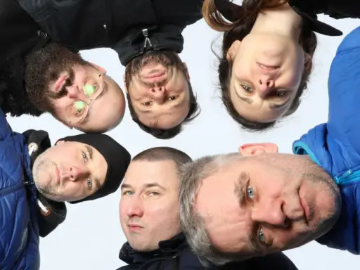 Grupa ludzi, w tym jeden z okularami, tworzy afro kolektyw. Wszyscy patrzą w obiektyw, tworząc ciekawe ujęcie.