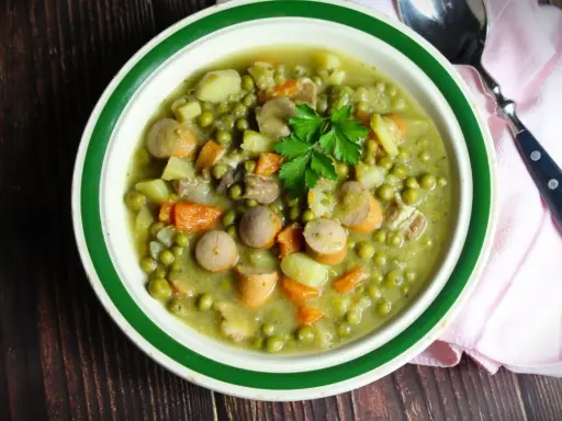 Herzhaftes Erbsensuppe Rezept mit Würstchen, Kartoffeln und Karotten, garniert mit Petersilie. Ein Klassiker für kalte Tage.