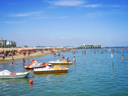 Spiaggia affollata a Gabicce, con ombrelloni colorati, gente in acqua e pedalò. Un'estate vivace al banana beach Gabicce.