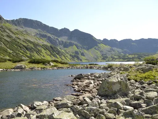 Kamieniste wybrzeże jeziora w Tatrach, idealne na wędrówkę szlakami turystycznymi Zakopane.