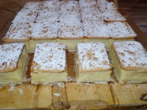 Pyszne napoleonki na krakersach, posypane cukrem pudrem, czekają na spróbowanie.