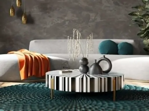 Nowoczesny salon w stylu feng shui z szarą kanapą, pomarańczowym kocem, czarno-białym stolikiem i turkusową podłogą.