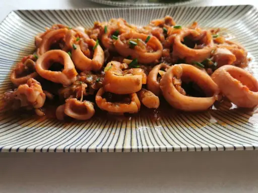 Calamares a la riojana, un plato tradicional español con aros de calamar cocinados en una sabrosa salsa de tomate y pimientos.