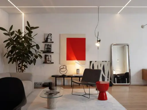 Salotto moderno con divano, poltrona, tavolino in vetro e un tocco di stile bauhaus nell'arredamento.