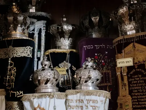 Srebrne korony i ozdobne zwoje Tory, przypominające o królewskiej chwale i mądrości z Psalmu 21.