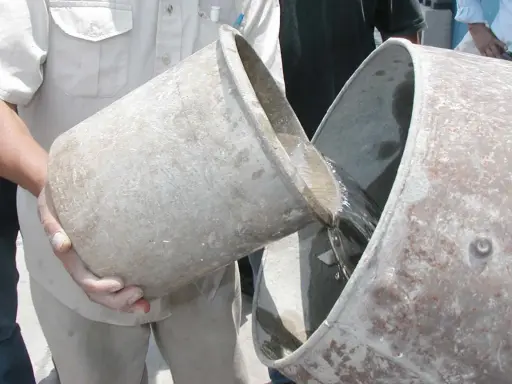 Se vierte agua de un cubo a otro, preparándose para proporcionar cemento y agua.