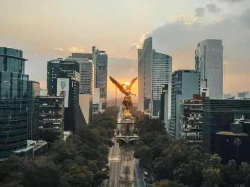 Goldene Viktoria-Statue im Sonnenuntergang, umgeben von modernen Wolkenkratzern in Mexico City.