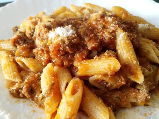 Penne al ragù di cinghiale, un piatto ricco e saporito, condito con abbondante sugo e una spolverata di parmigiano.