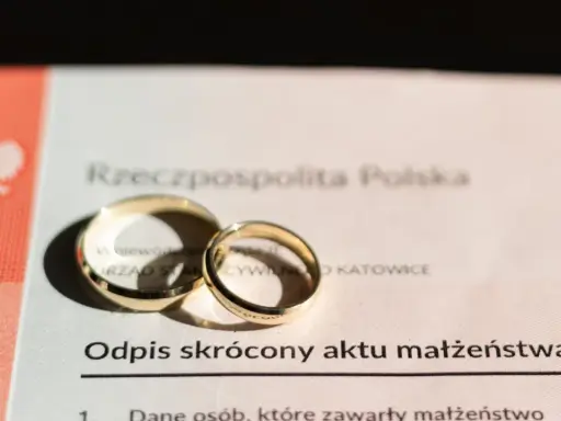 Dwa złote obrączki na odpisie skróconym aktu małżeństwa. Dokument potwierdza, ile jest ważny akt małżeństwa.