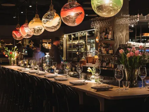 Elegant bar i en michelin restaurang Stockholm. Vackra glaslampor, blommor och uppdukade bord skapar en lyxig atmosfär.