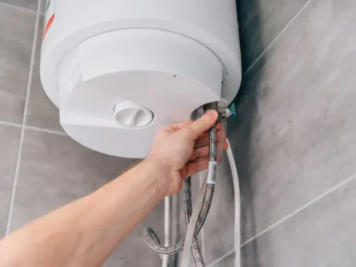 Mano che collega un tubo a uno scaldabagno a gas. La domanda è: quanto dura uno scaldabagno a gas?