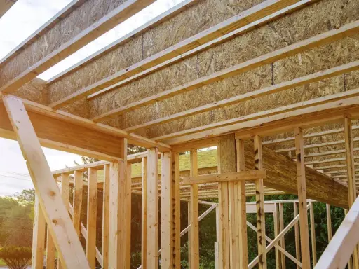 Estructura de madera de una casa en construcción, mostrando las partes de un apeo y vigas del techo.