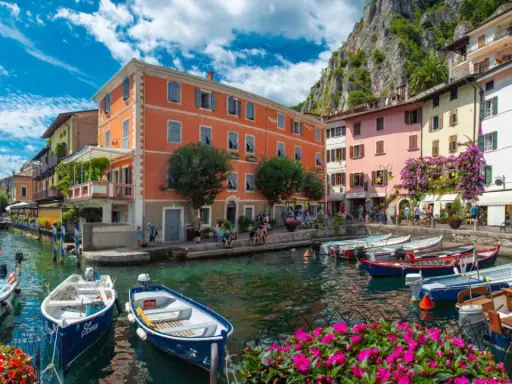 Colorate case sul lungolago di Limone sul Garda, con barche ormeggiate e fiori vivaci. Un luogo incantevole da scoprire, perfetto per capire cosa visitare a Limone sul Garda.