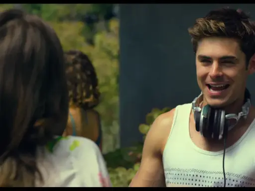 Il cast di We Are Your Friends, Zac Efron con le cuffie al collo, sorride mentre parla con qualcuno fuori campo.
