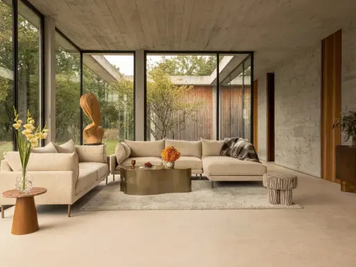 Un salon moderne avec un canapé beige, une table basse dorée et des touches de couleur orange et verte. Une question se pose : quelle couleur assortir avec le beige pour un intérieur chaleureux ?