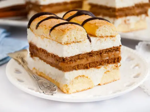 Szybkie ciasto z serkiem mascarpone, przełożone kremem i biszkoptem, ozdobione czekoladą. Idealne na deser.
