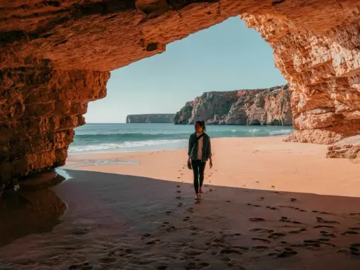 Frauen spazieren am Strand unter Felsbögen, ein perfekter Moment auf einer 14-tägigen Rundreise Portugal.