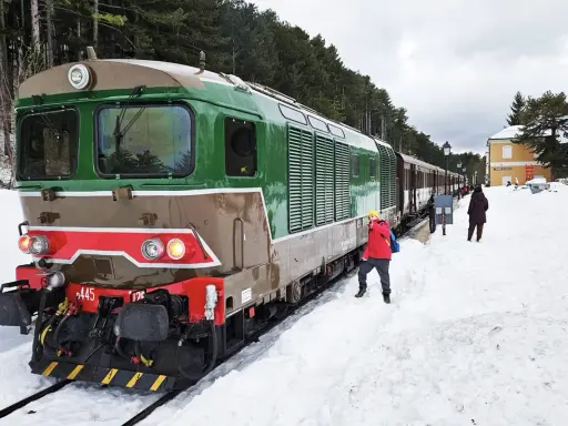 Treno della Transiberiana d'Abruzzo in sosta, con passeggeri sulla neve. Le tappe di questo viaggio unico tra montagne innevate.