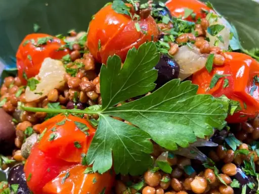 Ensalada de lentejas con tomates cherry, aceitunas negras y perejil fresco. Un plato saludable y lleno de sabor.