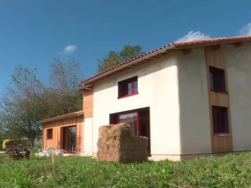 Maison écologique en paille, un projet de prix maison en paille clé en main. Le bâtiment est en cours de finition, avec des murs enduits et des accents de bois.