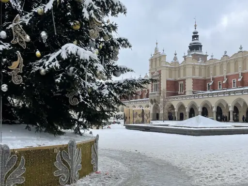 Świąteczna choinka na Rynku Głównym w Krakowie, otoczona śniegiem. To jedna z głównych kraków atrakcje zimą.